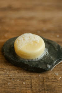 Een gebruikte, natte shampoo bar met schuim op een stenen zeepschaaltje – voorbeeld van een syndet bar bij het onderwerp wat is het verschil tussen natuurlijke zeep en gewone zeep